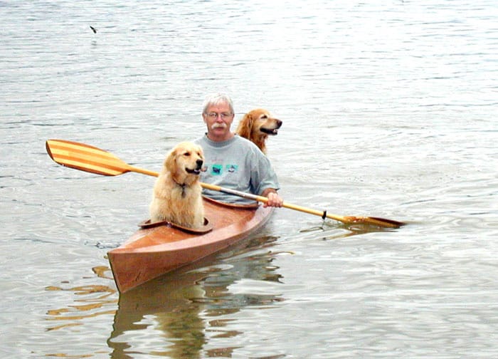 Мужчина и две собаки в лодке